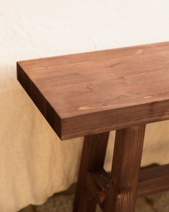 Gandía - Banqueta de madera maciza en tono nogal de 100x50cm